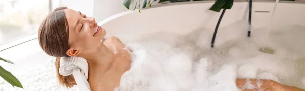 Ontspannen vrouw op zoek gelukkig terwijl het nemen van bubbelbad in haar mooie badkamer versierd met planten — Stockfoto