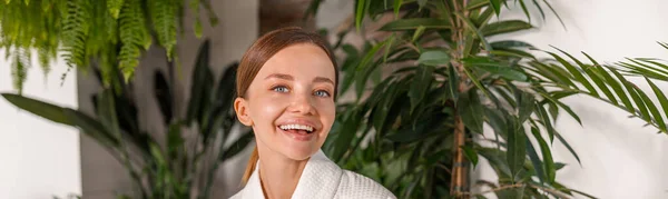 Opgewonden jonge vrouw met een fles met gel wassen terwijl ze in de badkamer versierd met planten — Stockfoto