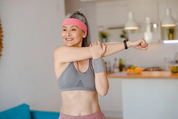 Mujer alegre estirando las manos durante el entrenamiento en casa — Foto de Stock