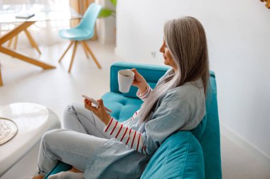 Çay içen ve akıllı telefon kullanan bir kadın.