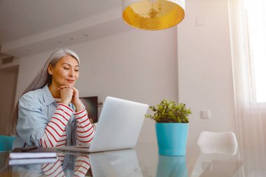 Evde modern taşınabilir dizüstü bilgisayarda çalışan bir kadın.