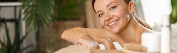 Portrait of lovely young woman smiling at camera while taking care of her body at tropical spa resort — Stock Photo, Image