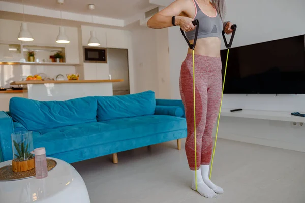 Sportieve vrouw doet oefening met weerstand trekken touw thuis — Stockfoto
