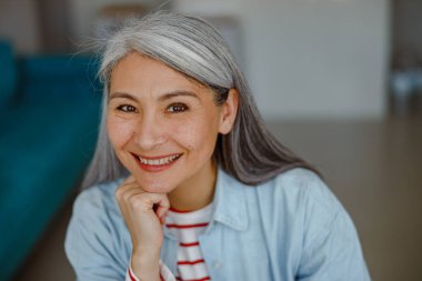 Neşeli kadın elleriyle başını kaldırıyor ve gülümsüyor.