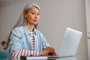 Evinde dizüstü bilgisayar kullanan bir kadın.