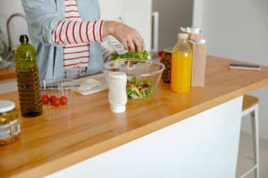 Kadın eli, sebze salatasıyla marulu kaseye koyuyor.