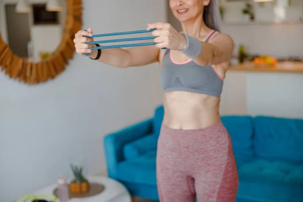 Mulher fazendo exercício com braço banda de resistência em casa — Fotografia de Stock