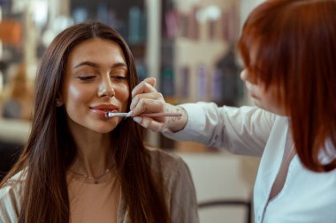 Profesyonel makyaj sanatçısı güzellik salonunda fırçayla ruj sürüyor.