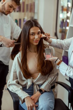 Profesyonel makyaj ve kuaförde saç stili yaptırırken gülümseyen kadın müşteri