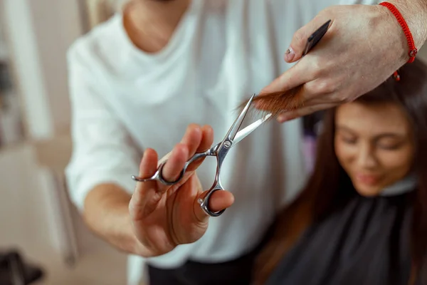 Peluquero sosteniendo tijeras en sus manos y cortando el pelo del cliente —  Fotos de Stock