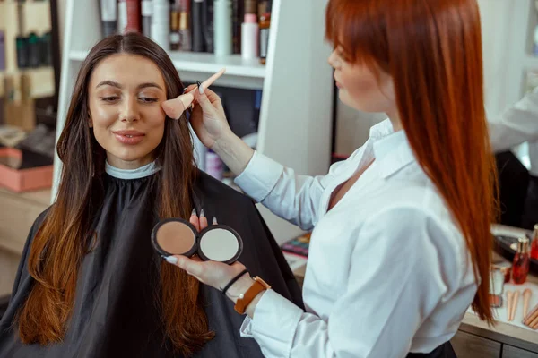 Professionell makeup artist tillämpa bronzer pulver med en borste i skönhetssalong — Stockfoto