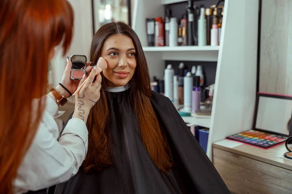 Junge Kundin bekommt Make-up-Rouge-Puder mit Pinsel auf die Wange — Stockfoto