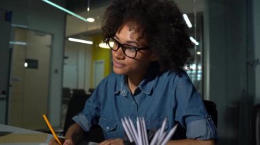Genç gülümseyen Afrikalı Amerikalı kadın akşam ofisinde çalışıyor.