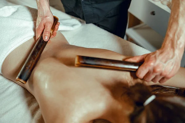 Manliga massör händer gör rygg massage till kvinnlig klient med ihåliga bambu käppar — Stockfoto