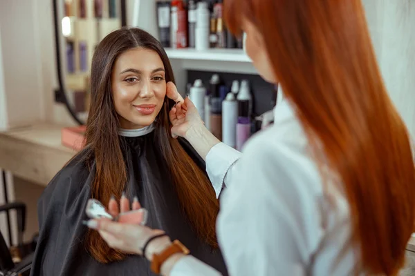 Gesicht einer jungen Frau, die mit einem Pinsel Rouge Puder auf ihre Wange bekommt — Stockfoto