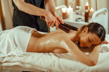 Rahat kadın içi boş bambu bastonlarıyla sırt masajı yaptırıyor.