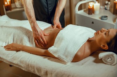 Rahatlamış bayan müşteri spa salonunda mide masajı yaptırıyor.