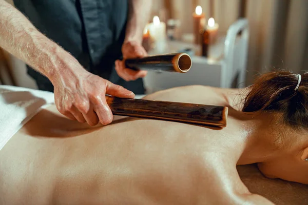 Terapeuta masculino fazendo massagem nas costas para a mulher usando bastões de bambu oco — Fotografia de Stock