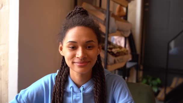 Hermosa joven sonriendo en un café mientras mira a la cámara. — Vídeos de Stock