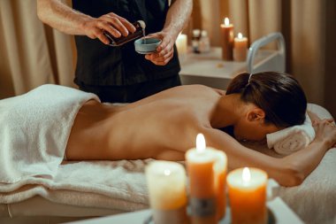 Masör terapist, omurga masajı yapmak için sıcak bitkiler hazırlıyor.