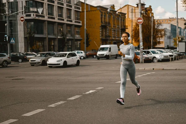Sportiva in grigio chiaro attiva usura correre all'aperto durante il giorno — Foto Stock