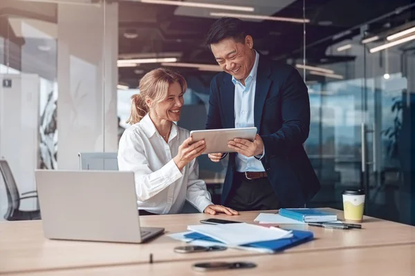 İş adamları proje için toplanıyor ve bunu dizüstü bilgisayar ve tablet kullanarak tartışıyorlar.