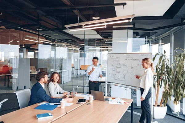 Asiático hombre y mujer conduce una reunión para los empleados cerca de un rotafolio y explica la estrategia de trabajo — Foto de Stock