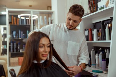 Professional male hairdresser cutting hair of woman at beauty salon
