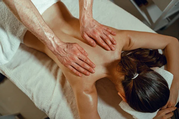 Top view massör man gör rygg massage med olja till en kvinna i spa salong — Stockfoto