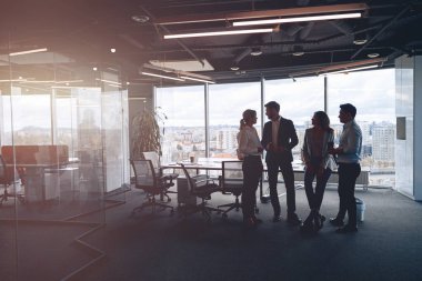 Modern ofiste panoramik pencerelere karşı duran iş ekibi