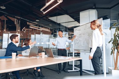 Olgun Asyalı antrenör veya konuşmacı toplantıda çeşitli iş adamlarına ters yüz grafiği sunumu yap