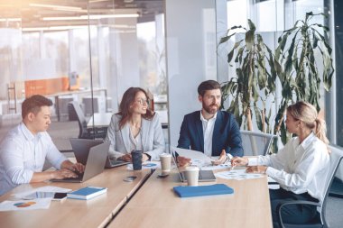 Şirket işletme ekibi ve yönetici, modern ofiste panoramik pencereli bir toplantı odasında.