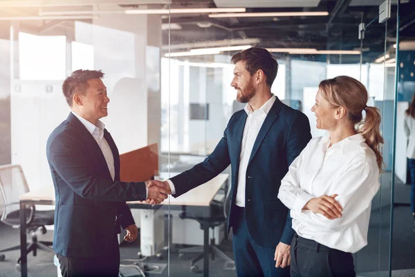 Takımımıza hoş geldiniz, modern modern modern erkekler modern ofiste el sıkışıyorlar.