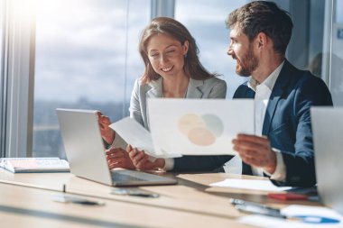 Two business people during work meeting in modern office explaining statistics data to each other