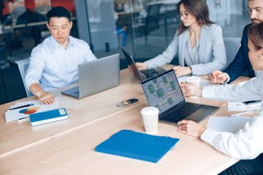 Odaklanmış iş adamları ofiste konferans sırasında cihazlar kullanıyor ve konuşuyorlar.