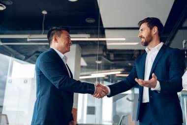 Modern ofisteki başarılı anlaşmadan sonra iki olgun iş ortağı tokalaşıyor.