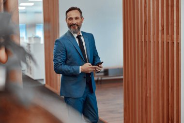 Ofiste cep telefonu kullanan mutlu sakallı adam.