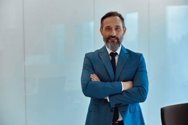 Kameraya poz veren şık takım elbiseli beyaz adam.