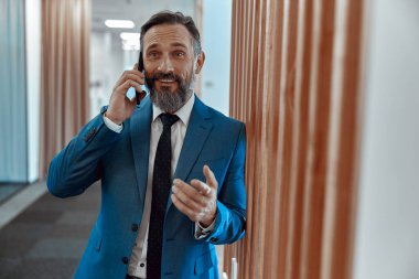 Modern aydınlık ofis içinde iş adamı cep telefonuyla konuşuyor.