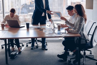 Close up team of businessmen working and communicating together in office with panoramic windows