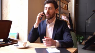 Genç çekici iş adamı kafede cep telefonuyla konuşuyor. Zarif adam cep telefonundan konuşuyor..