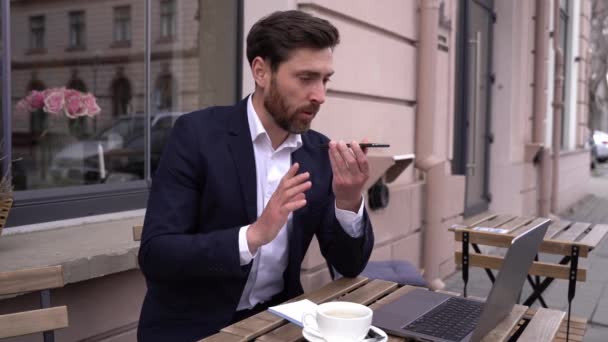 Bel homme caucasien dans la suite envoyer un message vocal sur smartphone. Homme d'affaires bavarder. — Video