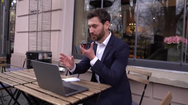 Attractive Caucasian young businessman in suite recording voice message on mobile phone. — Stock Video