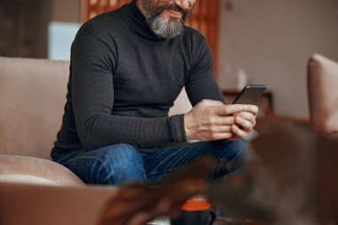 Koltukta oturan ve cep telefonu kullanan mutlu adam.