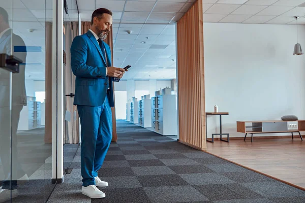 Şık takım elbiseli bir işadamı akıllı telefondan mesaj yazıyor.