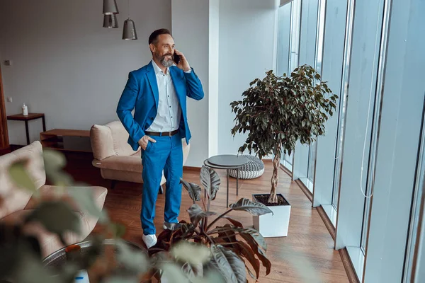 Pencerenin önünde duran bir adam telefonla konuşmaktan zevk alıyor.