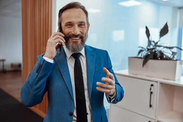 Gülümseyen sakallı adam telefonda konuşmaktan zevk alıyor.