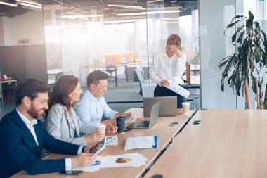 Ofisteki iş arkadaşlarıyla iş görüşmesinde gülümseyen bayan patron. 