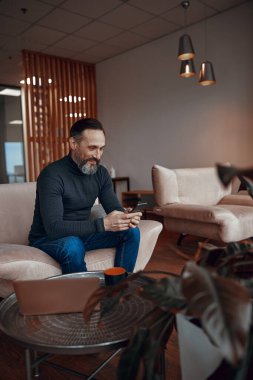 Gülümseyen sakallı adam telefonda yazıyor.