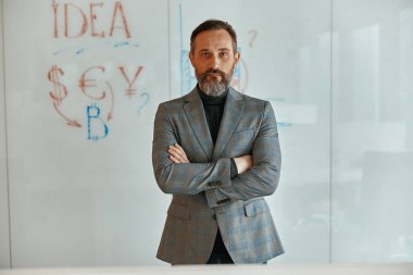 Ofisteki kendine güvenen beyaz adam kameraya bakıyor.